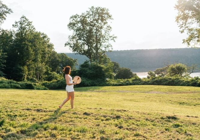 A woman wearing white shorts and top walking in a field